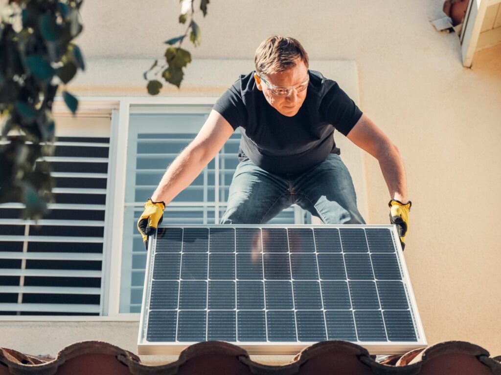 A man installing a solar panel on a roof